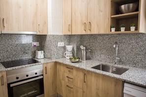 A kitchen with granite countertops, stainless steel appliances, wooden cabinets, and a dish rack. - New Listing (Salou)
