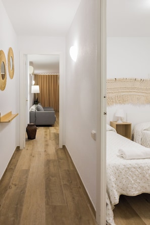 Ein Hotelzimmer mit einem Bett, einem Nachttisch, einer Lampe, einem kleinen Tisch und einer wandhängenden Makramee-Dekoration.