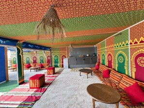A room with patterned walls, a sofa, a table, and a hanging light fixture.