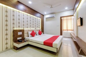 A hotel room with a bed, bedside table, and a wall-mounted TV. - Hotel O Riyansh Palace (Indore)