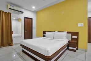 A hotel room with a bed, bedside table, and a mirror. - Collection O Jineshwari Hotel (Indore)