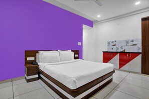 A bedroom with a bed, a nightstand, a red and white cabinet, and a purple wall. - Collection O Jineshwari Hotel (Indore)