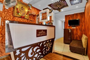 A reception area with a sign, a television, and a sofa. - Collection O Jineshwari Hotel (Indore)