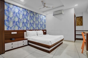 Une chambre d’hôtel équipée d’un lit, d’un bureau, d’une chaise, d’un climatiseur et d’un ventilateur de plafond.