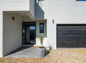 Un bâtiment moderne doté d’une porte de garage, d’une plante en pot et d’une allée gravillonnée.