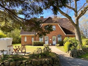 A brick house with a tiled roof, a stone pathway, and a bench. - Holiday Apartment in Wyk on Fohr With Wi-fi (Wyk auf Foehr)