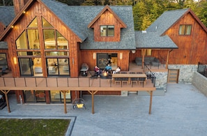 Une cabane en bois dotée d’une terrasse, de grandes fenêtres et d’un foyer extérieur.