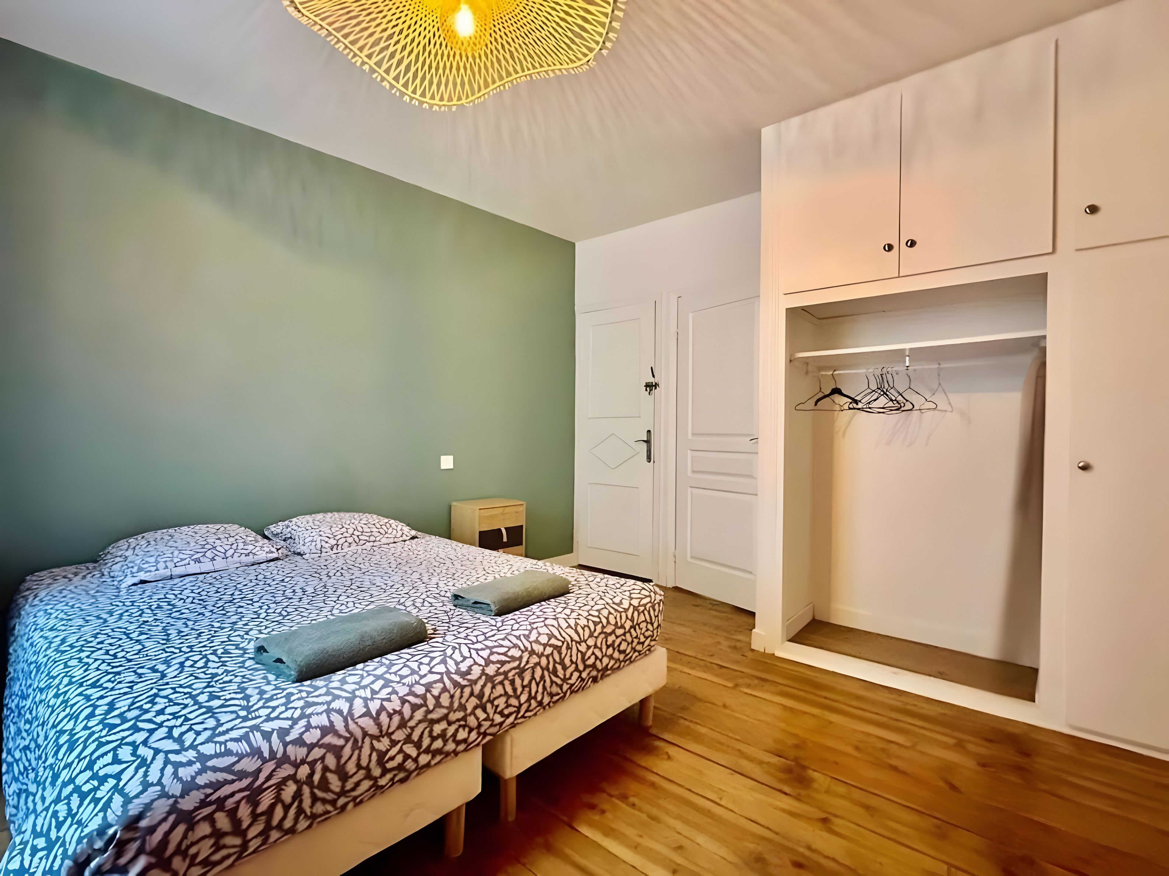A bedroom with a bed, a nightstand, a wardrobe, and a hanging closet.
