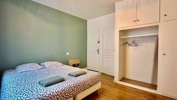 A bedroom with a bed, a nightstand, a wardrobe, and a hanging closet.