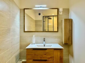 A bathroom with a white sink, wooden vanity, and a mirror above it. - Holiday Home 'Maison Jebari' (Carcassonne)