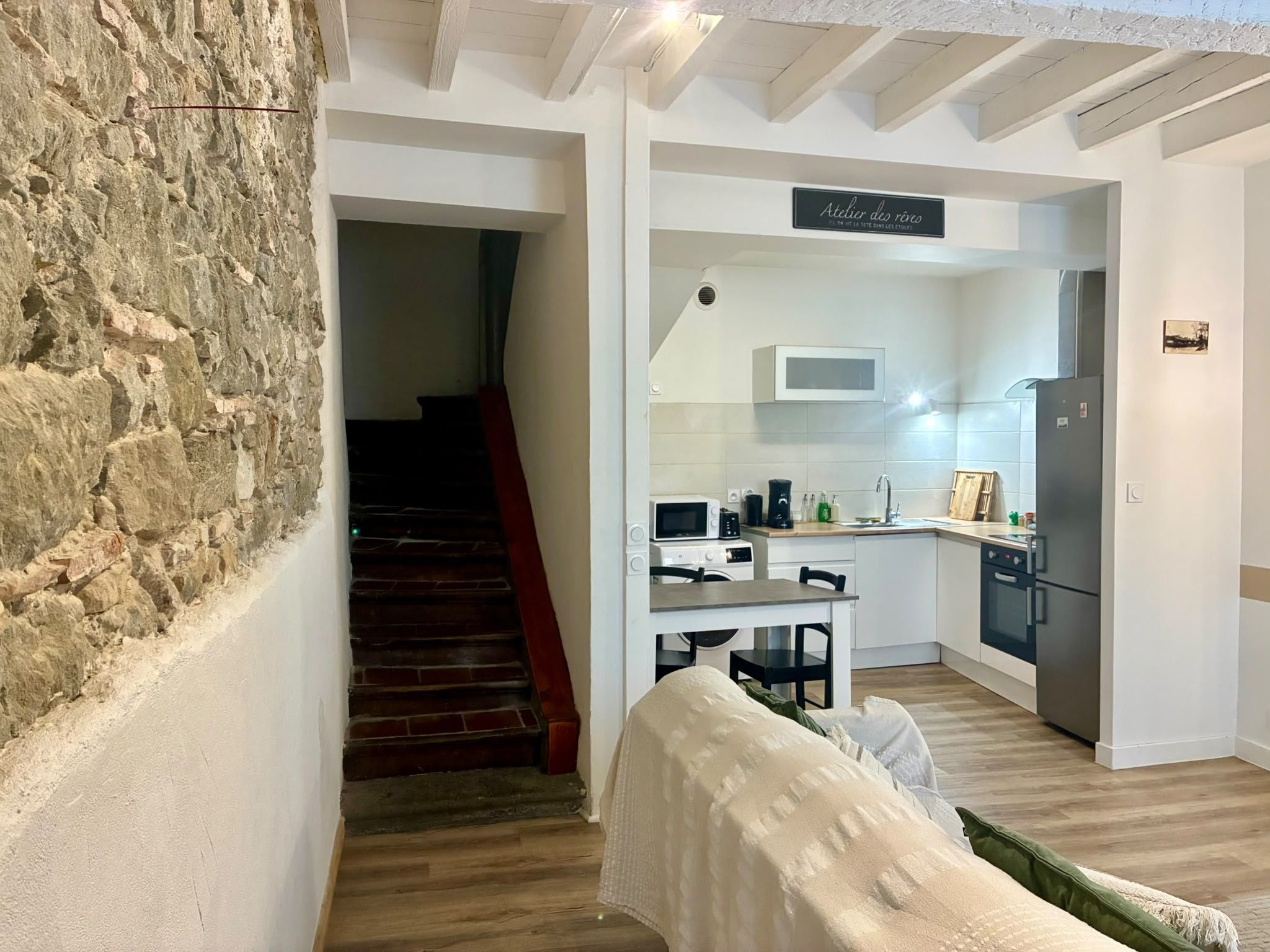 Ein modernes Interieur mit einer Steinwand, einer Treppe, einer Küchenzeile und einem Essbereich.