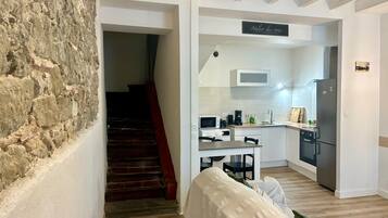 Ein modernes Interieur mit einer Steinwand, einer Treppe, einer Küchenzeile und einem Essbereich.