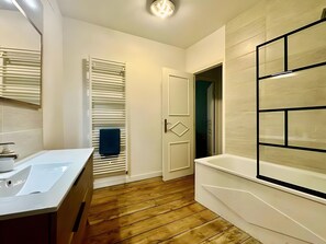 A modern bathroom with a wooden floor, a white sink, and a large mirror. - Holiday Home 'Maison Jebari' (Carcassonne)