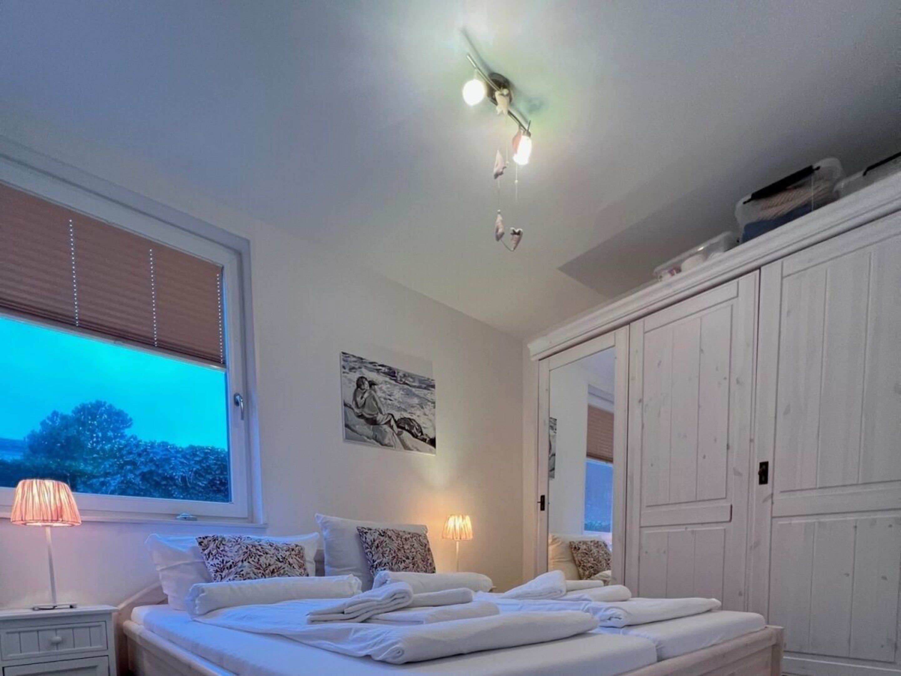 Una camera da letto con un letto, lampade sui comodini, un quadro e un armadio.