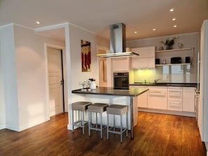 Una cocina moderna con una isla central, taburetes de bar y un horno empotrado.