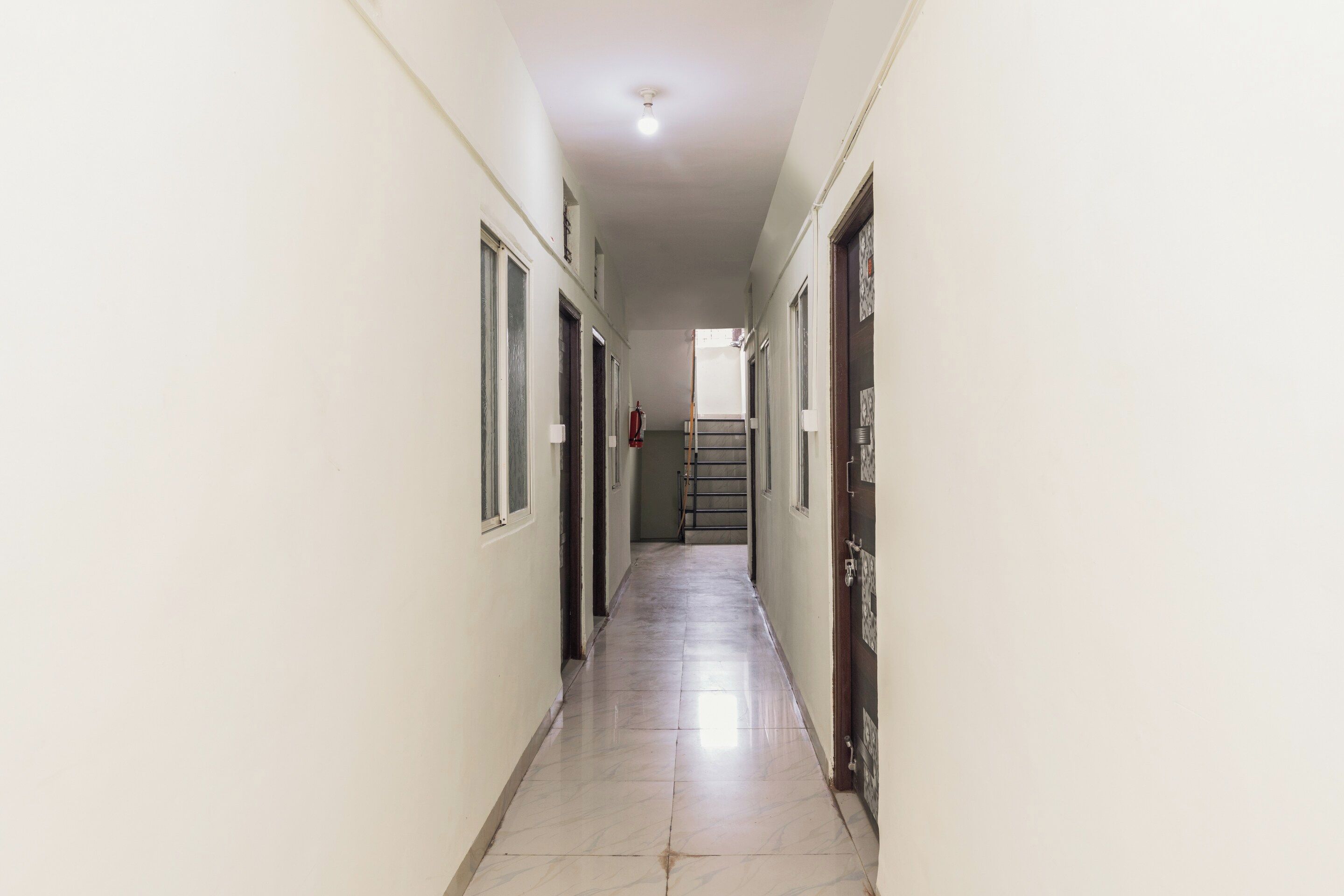 A long, narrow hallway with doors on both sides, leading to a staircase at the end.
