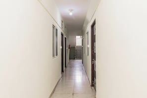Un pasillo largo y estrecho con puertas a ambos lados, que conduce a una escalera al final.