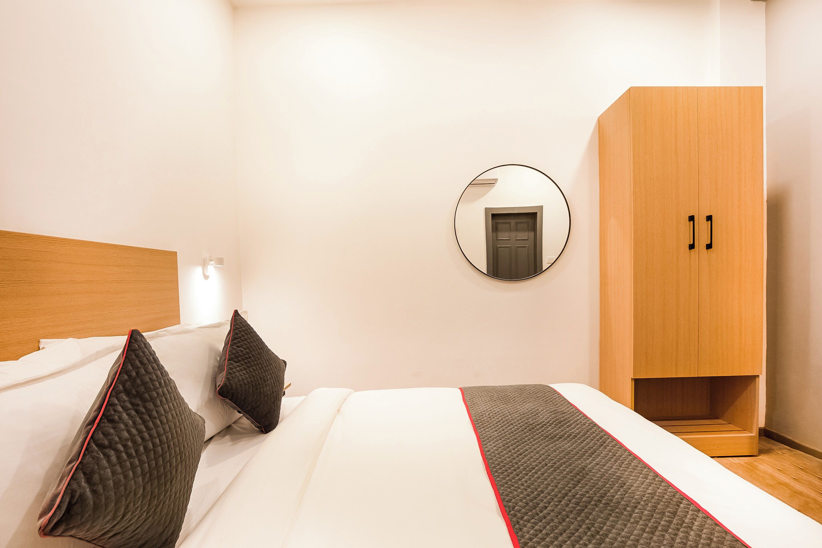 Quarto de hotel com cama, guarda-roupa, espelho e porta.