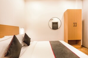Habitación de hotel con cama, armario, espejo y puerta.