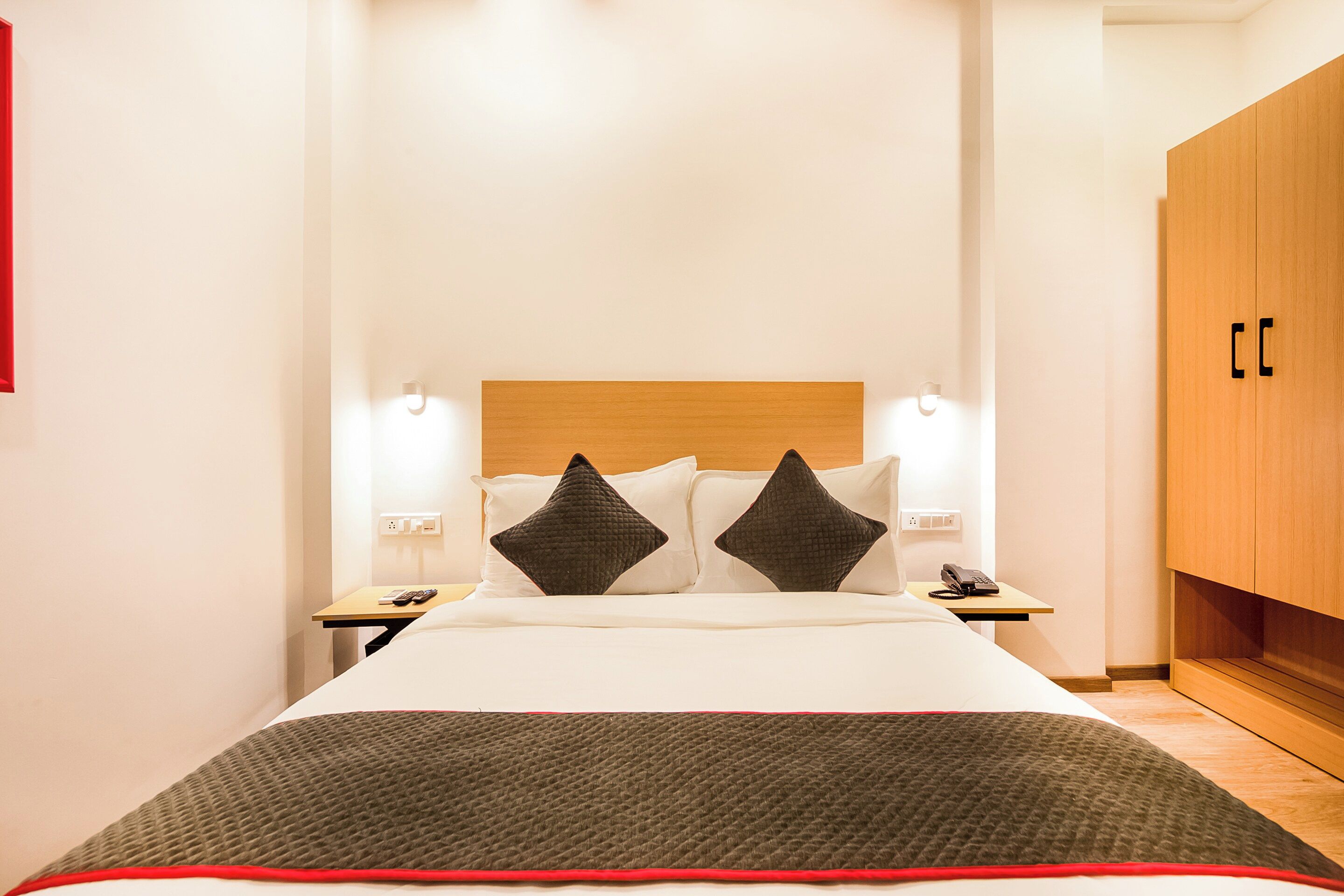 A hotel room with a bed, bedside tables, a telephone, and a wardrobe.