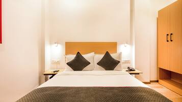 A hotel room with a bed, bedside tables, a telephone, and a wardrobe.