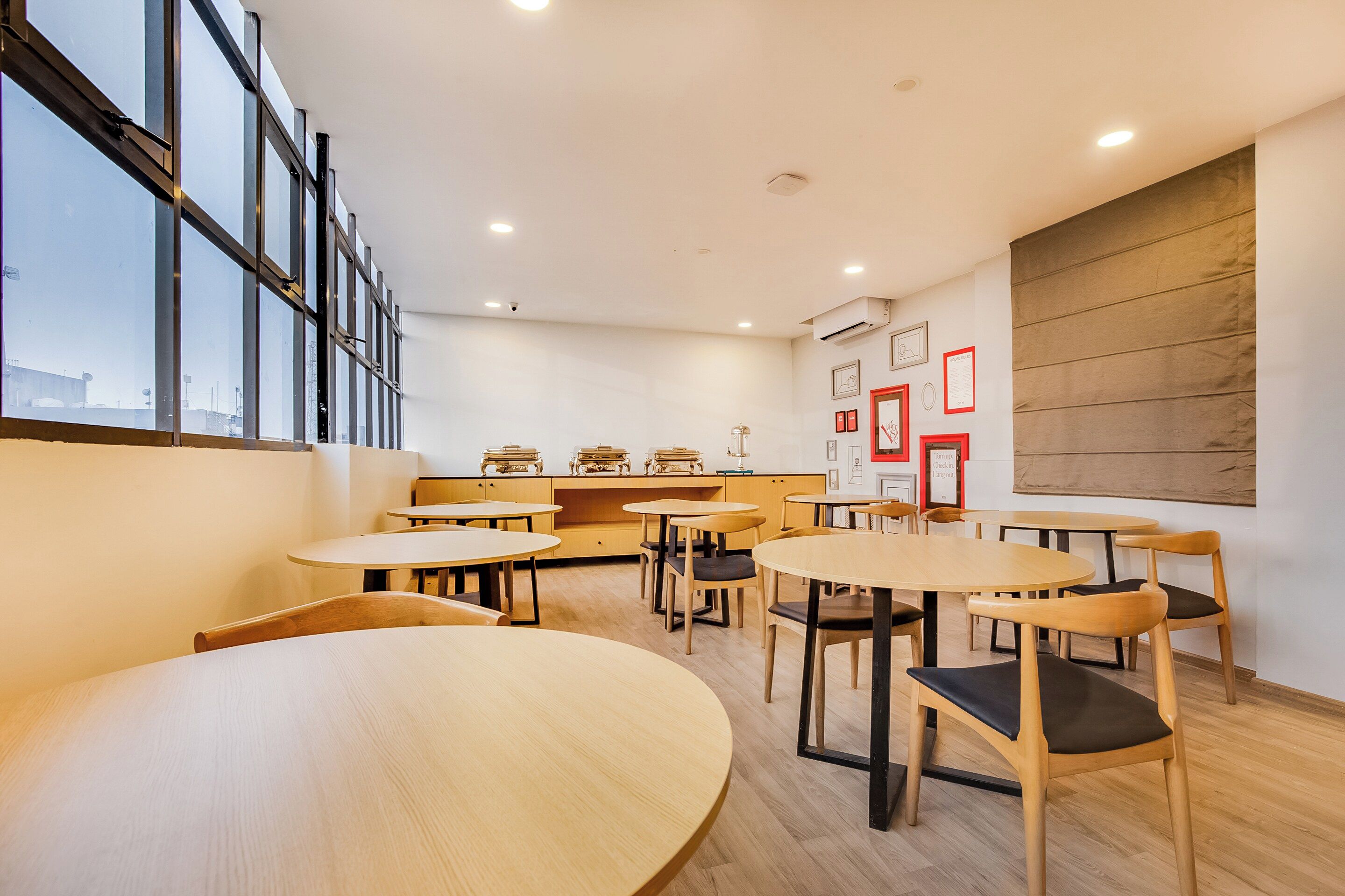 Een modern interieur met ronde tafels en stoelen, een groot raam en een wandairconditioning.