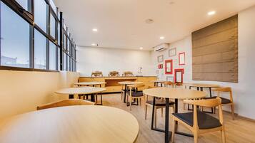 Een modern interieur met ronde tafels en stoelen, een groot raam en een wandairconditioning.