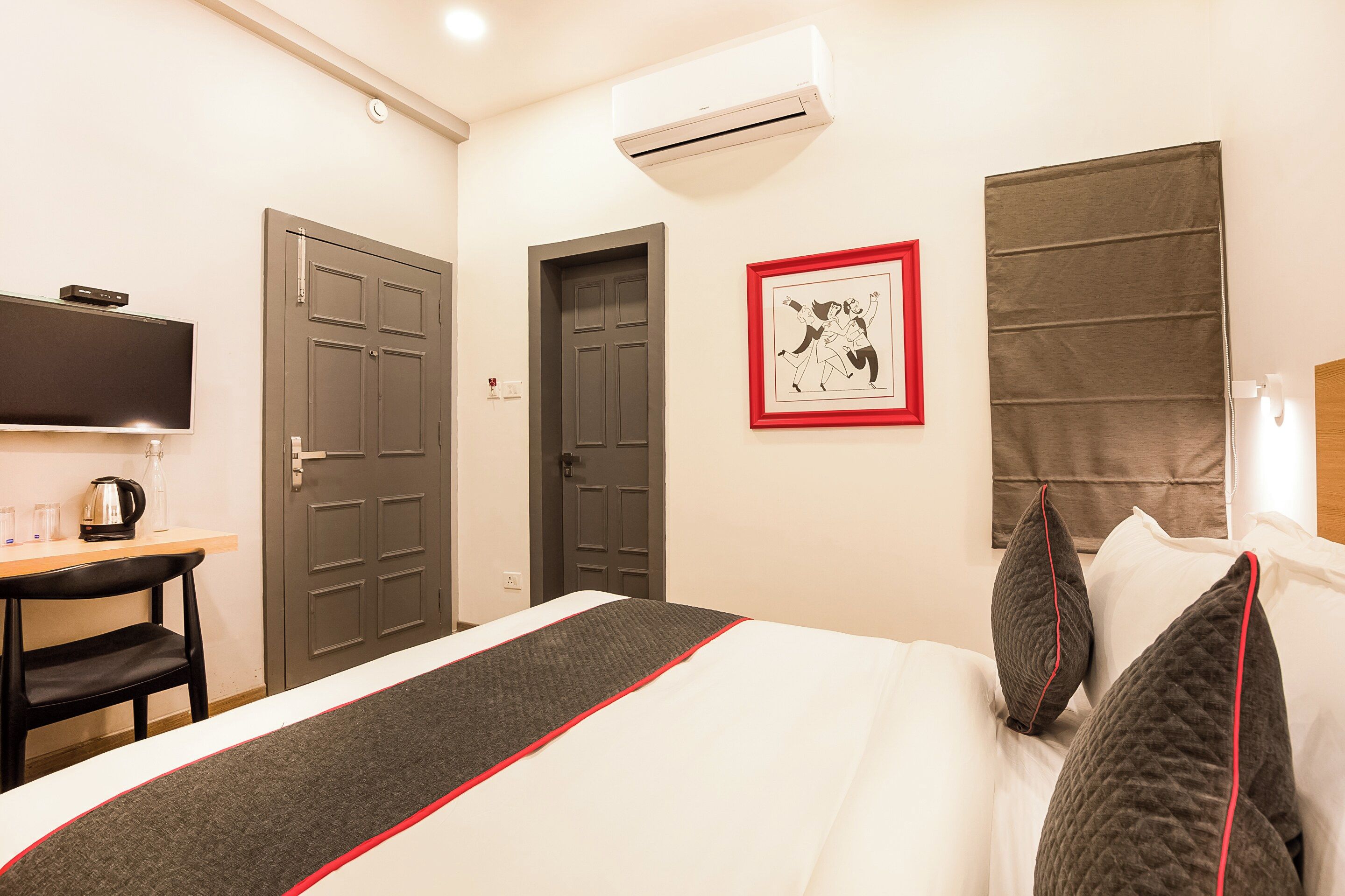 Una habitación de hotel con una cama, un escritorio, un televisor y un cuadro en la pared.