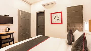 Una habitación de hotel con una cama, un escritorio, un televisor y un cuadro en la pared.