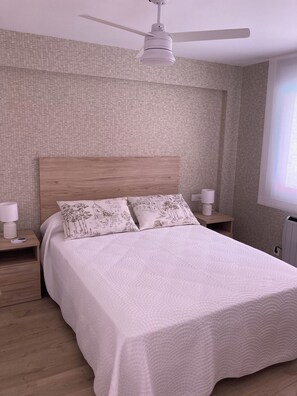 A bedroom with a bed, two bedside tables, a ceiling fan, and a window. - New Listing (Benicasim)