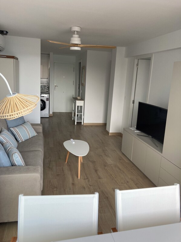A modern living room with a sofa, a small table, a TV, and a ceiling fan. - New Listing (Benicasim)