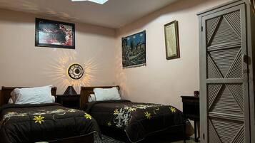 Un dormitorio con dos camas, una mesita de noche, una lámpara de pared decorativa y un armario.