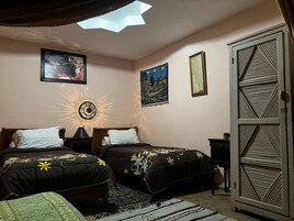 Un dormitorio con dos camas, una mesita de noche, una lámpara de pared decorativa y un armario.