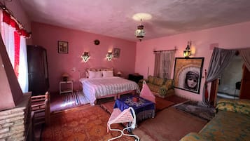 Un dormitorio con temática rosa, con cama, dos lámparas de pared, una lámpara colgante, un cuadro enmarcado y una mesita con lámpara.