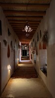 A narrow hallway with a wooden ceiling and walls adorned with hanging plants.