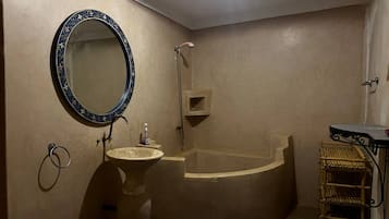 Un baño con lavamanos, bañera, espejo y repisa.