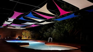 Un área de piscina exterior con piscina, rodeada de árboles y una zona de terraza.