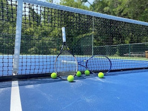 Een tennisbaan met een net, tennisrackets en tennisballen.