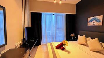 Habitación de hotel con cama, televisión, escritorio y ventana con cortinas.