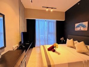 Habitación de hotel con cama, televisión, escritorio y ventana con cortinas.