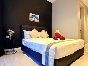 Una habitación de hotel con una cama, una mesita de noche, un jarrón con flores y un cuadro en la pared.