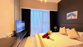 Una habitación de hotel con cama, televisión, ventana con cortinas y un cuadro en la pared.