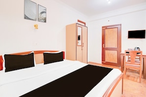 Una habitación de hotel con una cama, un armario, un escritorio y una televisión.