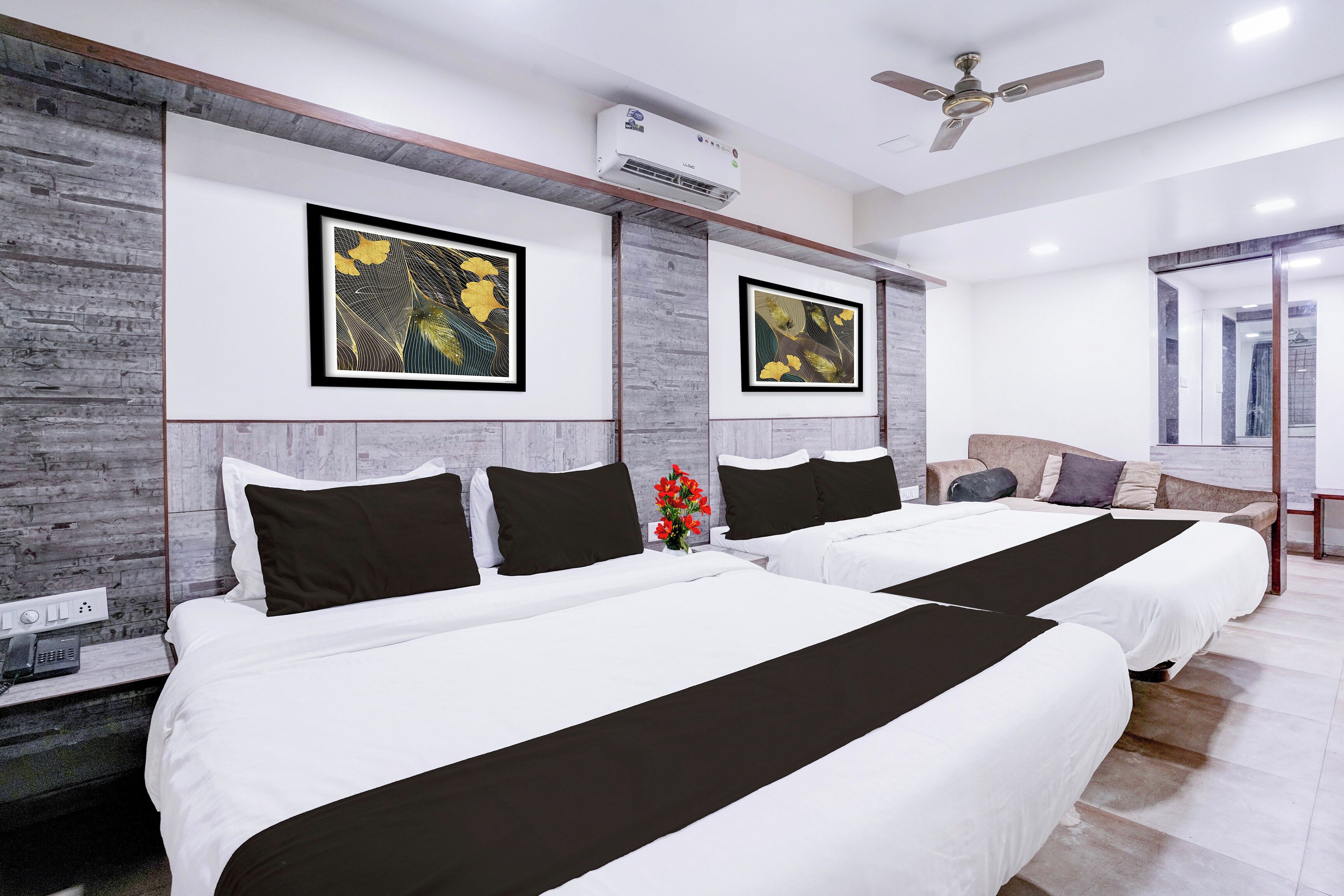 A hotel room with two beds, a ceiling fan, and artwork on the walls.