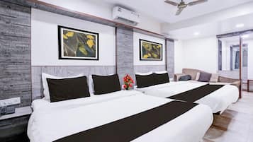 A hotel room with two beds, a ceiling fan, and artwork on the walls.