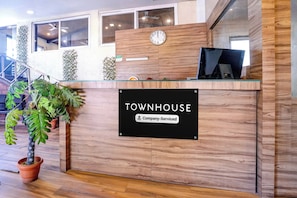 Una mesa de recepción con un cartel que dice 'TOWNHOUSE' y 'Servicio de empresa'.