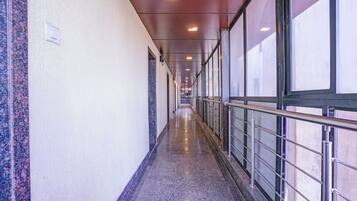 A long, narrow corridor with a polished floor, metal railings, and large windows on one side.