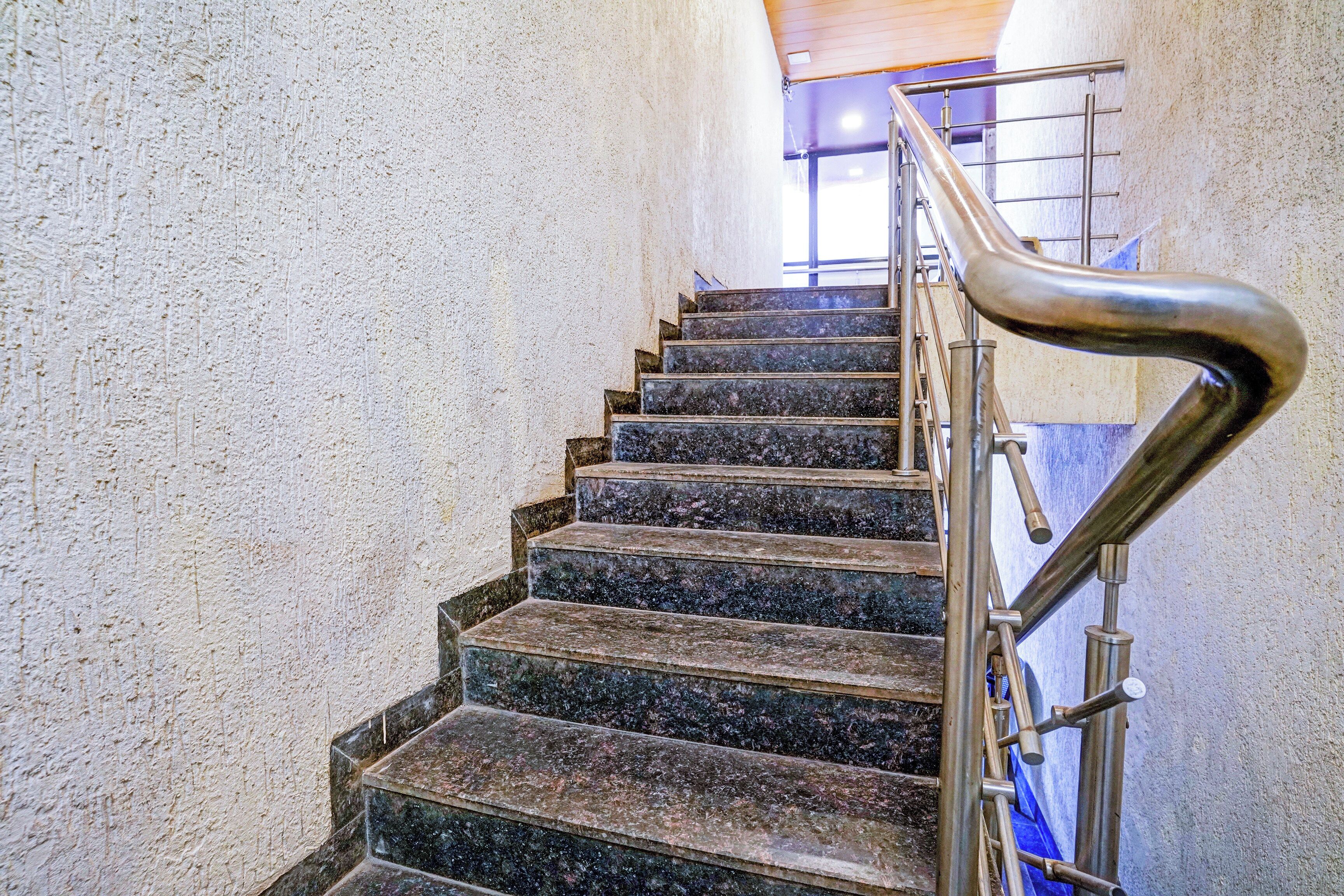 A staircase with a metal handrail and a textured wall.