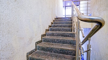 A staircase with a metal handrail and a textured wall.