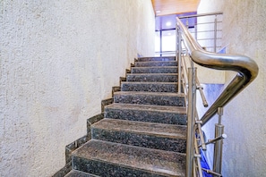 Una escalera con barandilla de metal y pared con textura.